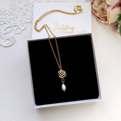 Collier minimaliste avec rose filigrane dorée et perles blanche en forme de goutte sur une fine chaîne dorée.