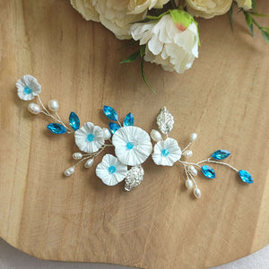 Bijou de cheveux avec fleurs blanches, feuilles argentées, perles naturelles et cristaux de strass bleu pour chignon de mariage