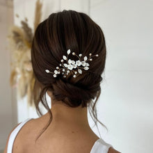 Charger l'image dans la galerie, Bijou de cheveux mariage avec fleurs blanches, feuilles et perles porté sur un chignon bas de mariée.