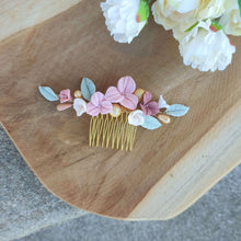 Charger l'image dans la galerie, Accessoire cheveux mariage sur peigne doré avec fleurs en porcelaine rose, feuilles vert tendre et perles, posé sur support en bois