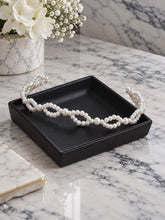Charger l'image dans la galerie, Bandeau de mariée en perles ivoire présenté sur vide-poche noir dans une mise en scène sur marbre.