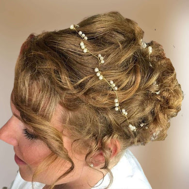 Bandeau minimaliste vague de sections de 3 perles sur fil doré sur chignon de mariage de cheveux blonds.