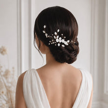 Charger l'image dans la galerie, Bijou de cheveux mariage finition dorée avec fleurs blanches et perles, porté sur le côté d’un chignon bas.