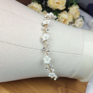Détail du serre-tête floral Carine : perles nacrées, fleurs blanches en porcelaine et strass pour coiffure de mariée