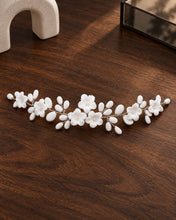 Charger l'image dans la galerie, Bijou de cheveux argenté à fleurs et boutons en porcelaine blanche sur fil argentée présenté à plat sur fond noyer foncé