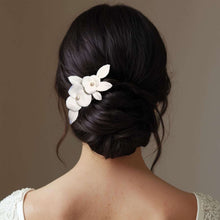 Charger l&#39;image dans la galerie, Bijou de cheveux Karisa en porcelaine blanche porté sur un chignon bas, accessoire floral expressif et fait main.