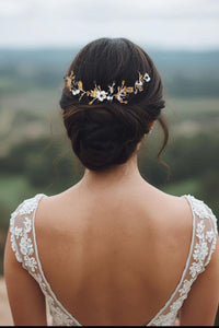 Bijou de cheveux noir et or porté dans un chignon bas élégant pour une mariée, en extérieur.