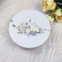 Charger l'image dans la galerie, Bijou de tête floral mariage avec fleurs blanches, perles et feuilles argentées, présenté à plat sur fond clair.