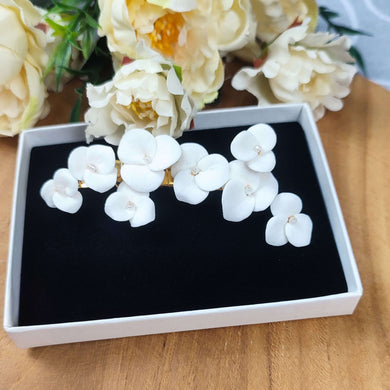Bijou de cheveux SIANA en porcelaine froide, fleurs blanches délicates présentées dans un coffret noir et blanc.