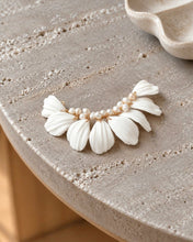 Charger l'image dans la galerie, Bijou de cheveux blanc pour mariée, composé de feuilles en porcelaine froide et de perles naturelles, posé sur une table en pierre.