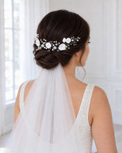 Charger l'image dans la galerie, Mariée brune vue de dos avec un chignon bas, un voile fixé sous la coiffure et une vigne argentée de fleurs blanches et perles.