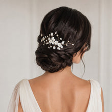 Charger l'image dans la galerie, Bijou de chignon mariée avec fleurs en porcelaine, perles et feuilles, finition argentée, porté sur chignon bas.