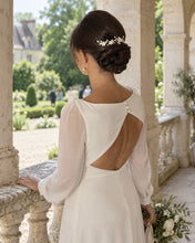 Charger l'image dans la galerie, Mariée en robe blanche vue de dos dans un jardin avec bijou floral sur chignon bas