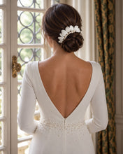 Charger l'image dans la galerie, Mariée vue de dos portant un bijou de cheveux en feuilles blanches en porcelaine froide et perles naturelles sur un chignon bas, avec une robe blanche à dos en V.