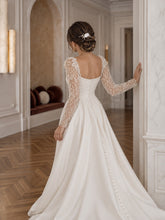 Charger l'image dans la galerie, Peigne cheveux floral blanc porté sur un chignon de mariée, vue plus éloignée avec robe de mariage blanche.