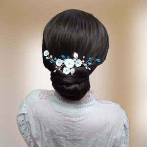 Vigne de cheveux avec fleurs blanches, feuilles argentées, perles naturelles et cristaux de strass bleu pour chignon de mariage