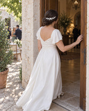 Charger l'image dans la galerie, Mariée entrant par la porte portant un bijou de cheveux en porcelaine blanche sur le côté d'un chignon bas