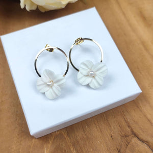 Boucles d'oreilles de mariage avec fleur blanche en porcelaine froide accroché sur un anneau à clou doré