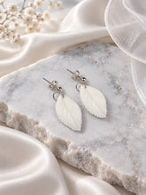Charger l'image dans la galerie, Boucles d’oreilles de mariage avec feuilles blanches en porcelaine et finition argentée, présentées à plat
