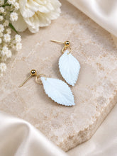 Charger l'image dans la galerie, Boucles d’oreilles de mariage avec feuilles blanches en porcelaine et finition dorée, présentées à plat