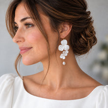 Charger l'image dans la galerie, Mariée de profil portant la boucle longue d’une paire de boucles d’oreilles asymétriques, avec fleurs blanches en porcelaine froide et perles.