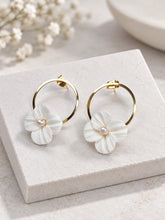 Charger l'image dans la galerie, Boucles d'oreilles florales avec cercles dorés de 2,5 cm, fleurs à quatre pétales en porcelaine blanche et perles centrales.