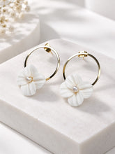 Charger l'image dans la galerie, Paire de boucles d'oreilles de mariage avec fleurs blanches sculptées en porcelaine froide et perles, sur un socle blanc.