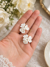 Charger l'image dans la galerie, Paire de boucles d’oreilles florales en porcelaine blanche avec perles et crochets dorés, présentée dans la paume d’une main pour montrer les dimensions réelles.