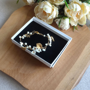 Bracelet floral de mariage avec perles nacrées, feuilles dorées et fleurs blanches en argile polymère