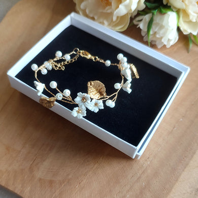 Bracelet floral de mariage avec perles nacrées, feuilles dorées et fleurs blanches en argile polymère