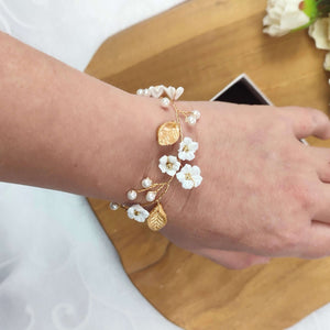 Bracelet floral de mariage champêtre chic avec fleurs blanches et feuilles dorées en porcelaine froide et perles nacrées