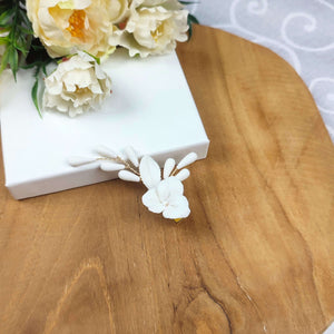 Clip cheveux mariage Daria en porcelaine blanche, accessoire floral délicat posé sur une boîte blanche.