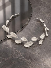 Charger l'image dans la galerie, Bijou de cheveux mariage à feuilles blanches en porcelaine froide sur fil argenté, présenté à plat sur une surface gris foncé.