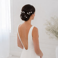 Charger l'image dans la galerie, Mariée brune de trois quarts portant des épingles étoiles blanches en porcelaine dans un chignon bas élégant.