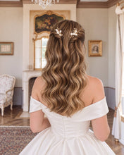 Charger l'image dans la galerie, Mariée de dos aux cheveux blonds ondulés, portant deux épingles avec fleurs et feuilles blanches en porcelaine froide, perles naturelles et cristaux transparents