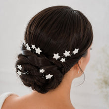 Charger l'image dans la galerie, Épingles à cheveux mariage étoiles en porcelaine blanche réparties autour d’un chignon bas brun de mariée.