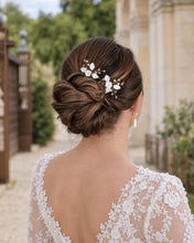 Charger l'image dans la galerie, Deux épingles à fleurs et feuilles blanches en porcelaine froide, perles naturelles et cristaux transparents, disposées au-dessus d’un chignon bas.