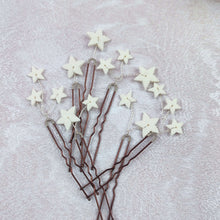 Charger l'image dans la galerie, Lot d’épingles cheveux mariage avec petites et grandes étoiles en porcelaine blanche présenté à plat sur fond texturé clair.