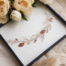 Charger l'image dans la galerie, Vigne de cheveux or rose avec feuilles, perles et cristaux présentée dans un écrin clair avec fleurs ivoire