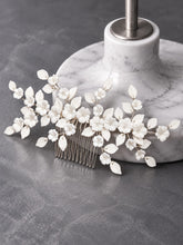 Charger l'image dans la galerie, Peigne cheveux mariage avec fleurs et feuilles en porcelaine blanche sur fil argenté, appuyé sur socle en marbre gris