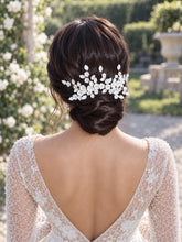 Charger l'image dans la galerie, Peigne de mariage floral en porcelaine blanche porté au-dessus d’un chignon bas de mariée, vue arrière