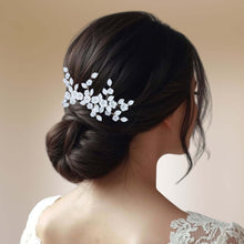 Charger l&#39;image dans la galerie, Peigne à cheveux Aude en porcelaine blanche porté sur un chignon bas, bijou de mariage élégant.