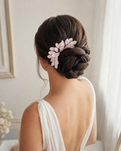 Charger l'image dans la galerie, Peigne floral blanc avec feuilles en porcelaine froide, glissé sur le côté d’un chignon bas brun texturé, avec robe de mariée à dos ouvert.