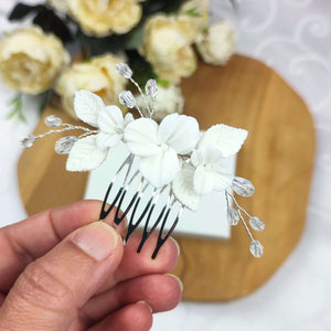 Bijou de cheveux sur peigne avec cristal transparent et fleurs et feuilles blanches en porcelaine froide pour chignon ou coiffure de mariage