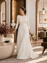Charger l'image dans la galerie, Mariée en robe blanche portant un serre-tête en perles nacrées avec chignon bas dans un intérieur élégant