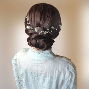 Vigne de cheveux avec feuilles argentées et perles sur chignon bas de mariage