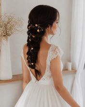 Charger l'image dans la galerie, Fine vigne de cheveux bohème romantique avec perles et feuilles dorées, portée par une mariée aux cheveux bruns sur longue tresse. Vue à 3/4 droite.