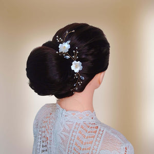 Vigne de cheveux florale avec perles nacrées, strass et fleurs blanches en satin sur chignon de mariage