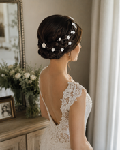 Charger l'image dans la galerie, Mariée vue de dos avec une tresse brune enroulée autour de la tête, ornée d’une vigne de cheveux fine avec fleurs blanches en porcelaine froide.