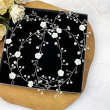 Charger l'image dans la galerie, Vigne de cheveux Adriana composée de perles, cristal et fleurs en porcelaine blanche, présentée à plat.